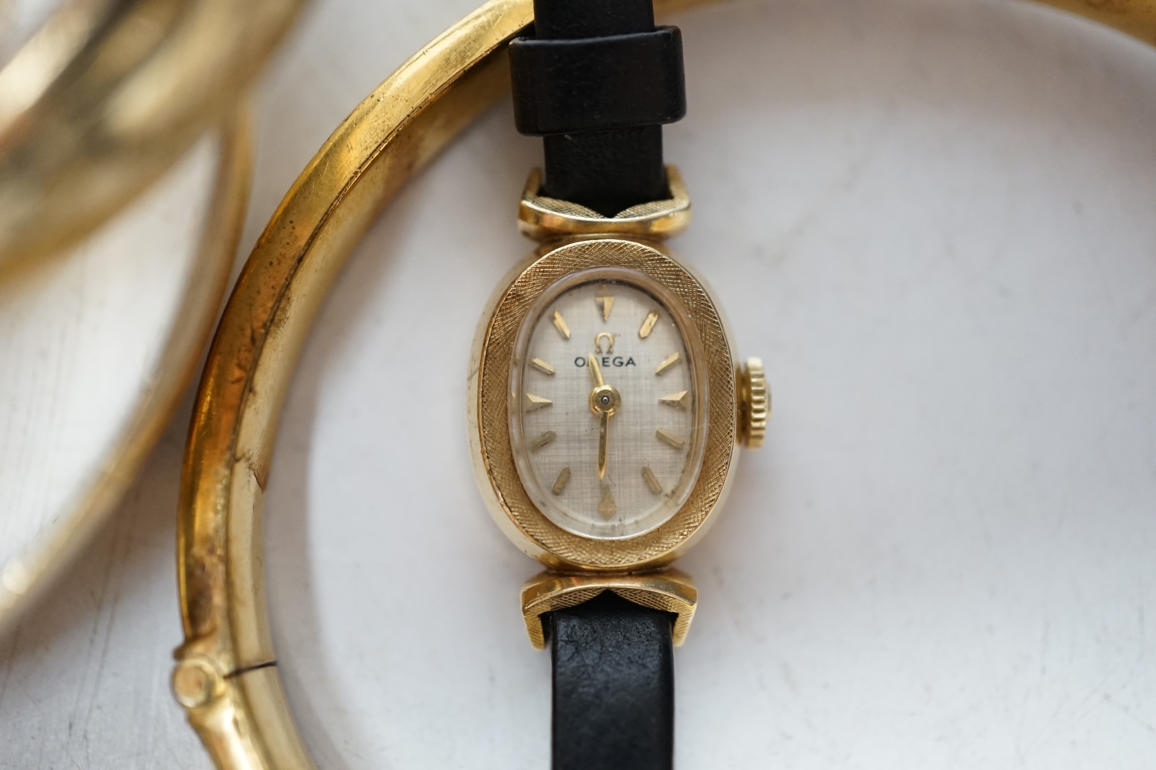 A lady's modern 14k Omega manual wind wrist watch and five assorted metal bangles. Condition - poor to fair